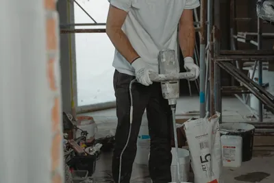 A construction worker using a mixer to prepare plaster indoors