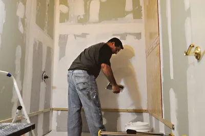 A tradesperson applying drywall mud to a wall during a bathroom renovation