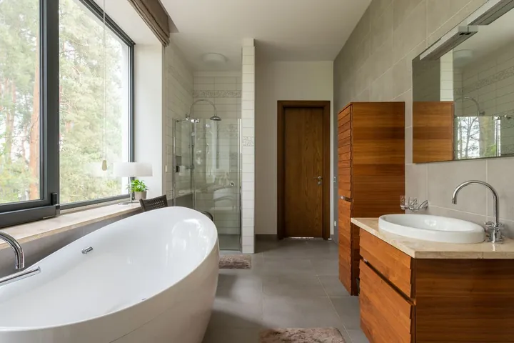 A bathroom with a rectangular mirror and a glass shower cabin in soft light